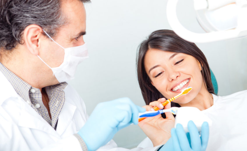 male dentisting shows a woman patient how to do proper dental hygine on her teeth at Dental Care Glebe, Sydney dental clinic